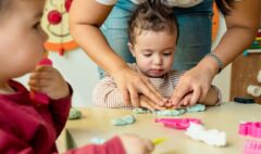 Child playing with Playdough, assisted by montessori teacher