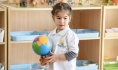 A nursery student holding a world map in a montessori environment
